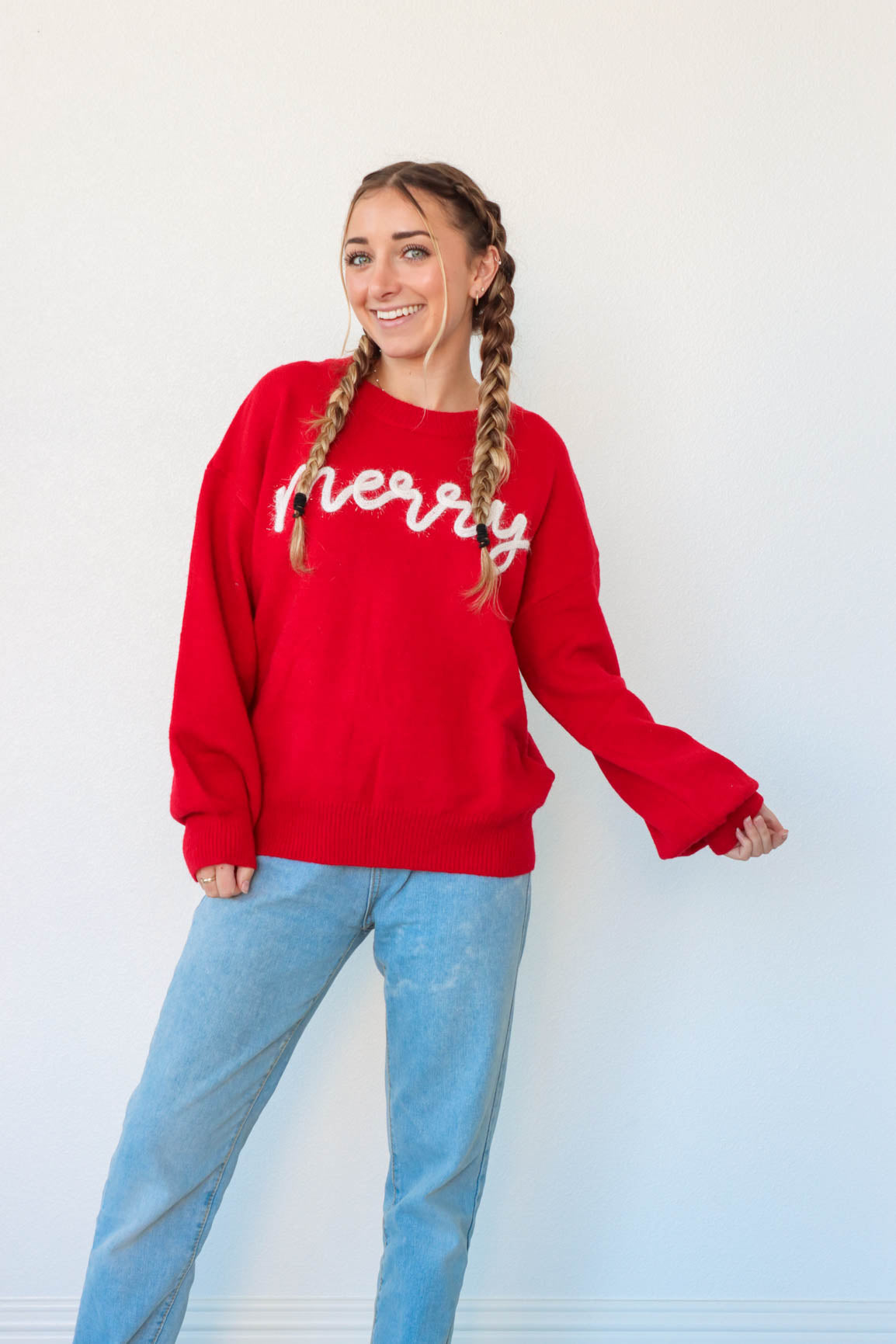 girl wearing red "merry" sweater with white tinsel lettering