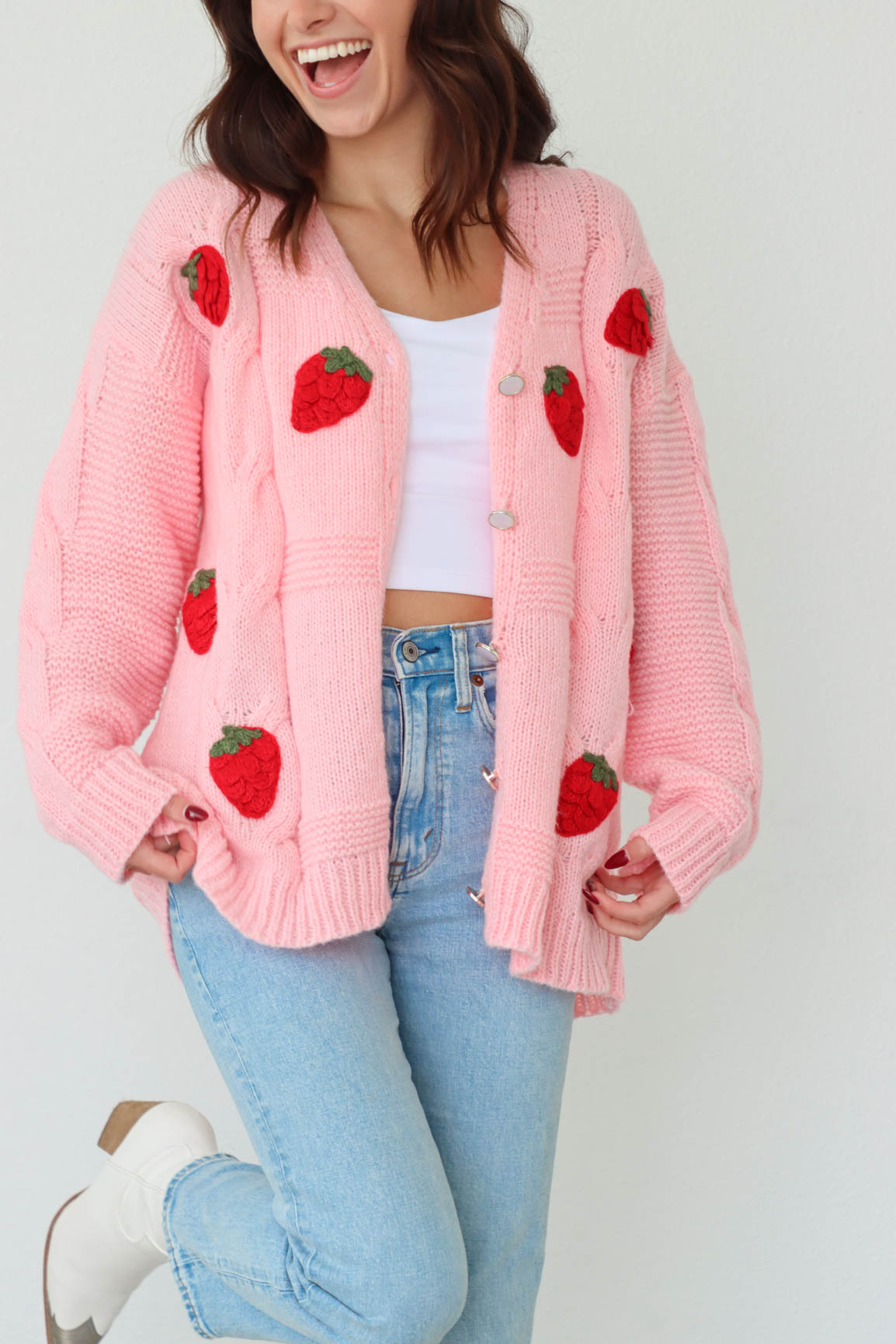 girl wearing pink knit cardigan sweater with red strawberry crochet detailing