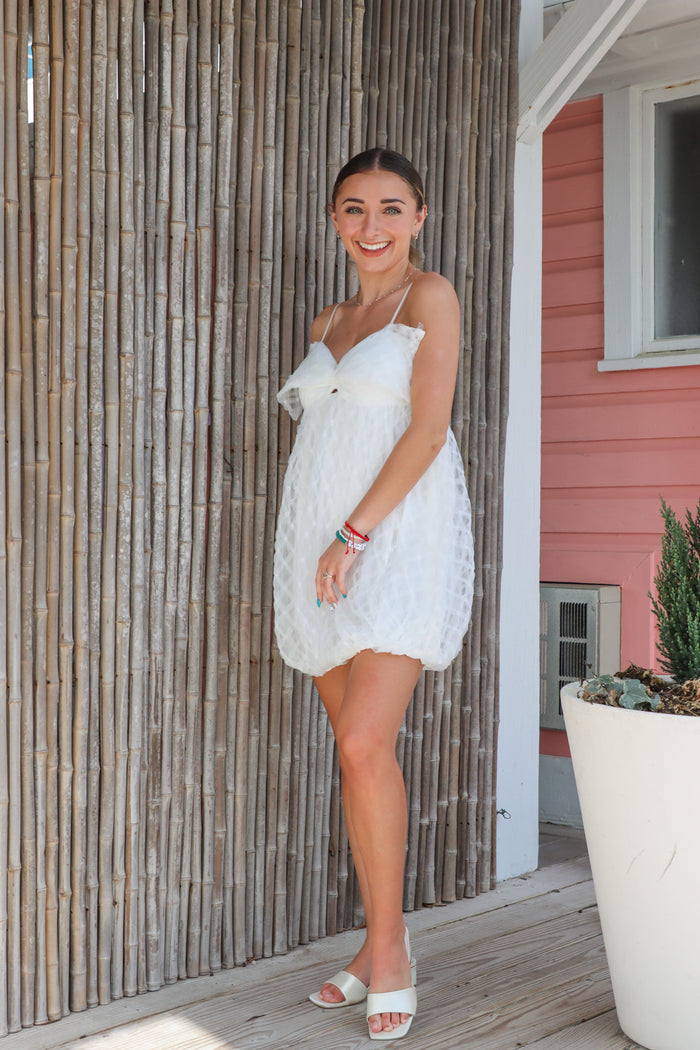 girl wearing white bubble dress with bow detailing