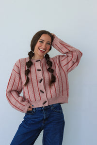 Person wearing a pink striped sweater and blue jeans against a white background