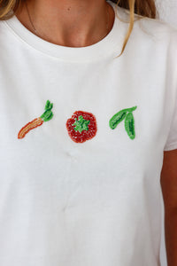White t-shirt with beaded carrot, tomato, and leaf design.