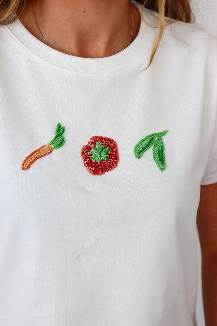 White t-shirt with beaded carrot, tomato, and leaf design.