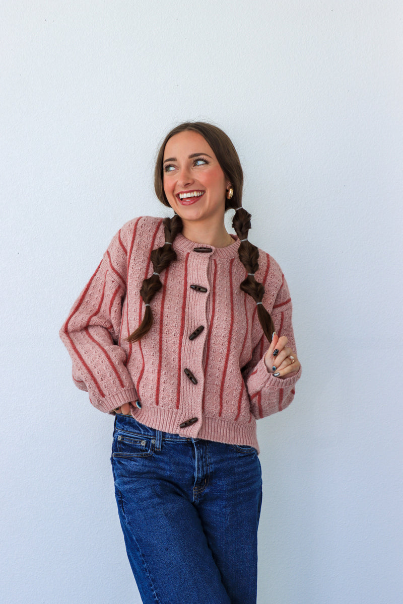 Woman wearing a pink and red striped sweater with buttons