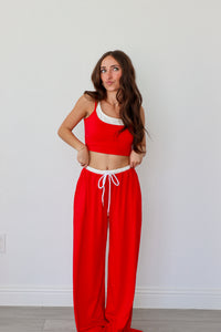 Woman wearing a red outfit with white accents against a plain background