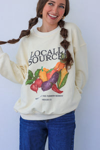 Person wearing a cream-colored sweatshirt with vegetable graphic and text