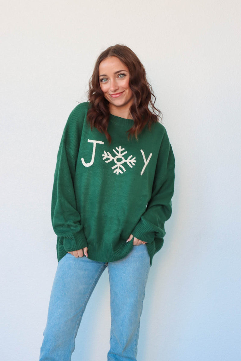 girl wearing green christmas sweater with "joy" graphic