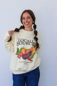 Woman wearing a cream-colored sweatshirt with a colorful graphic and text against a white background