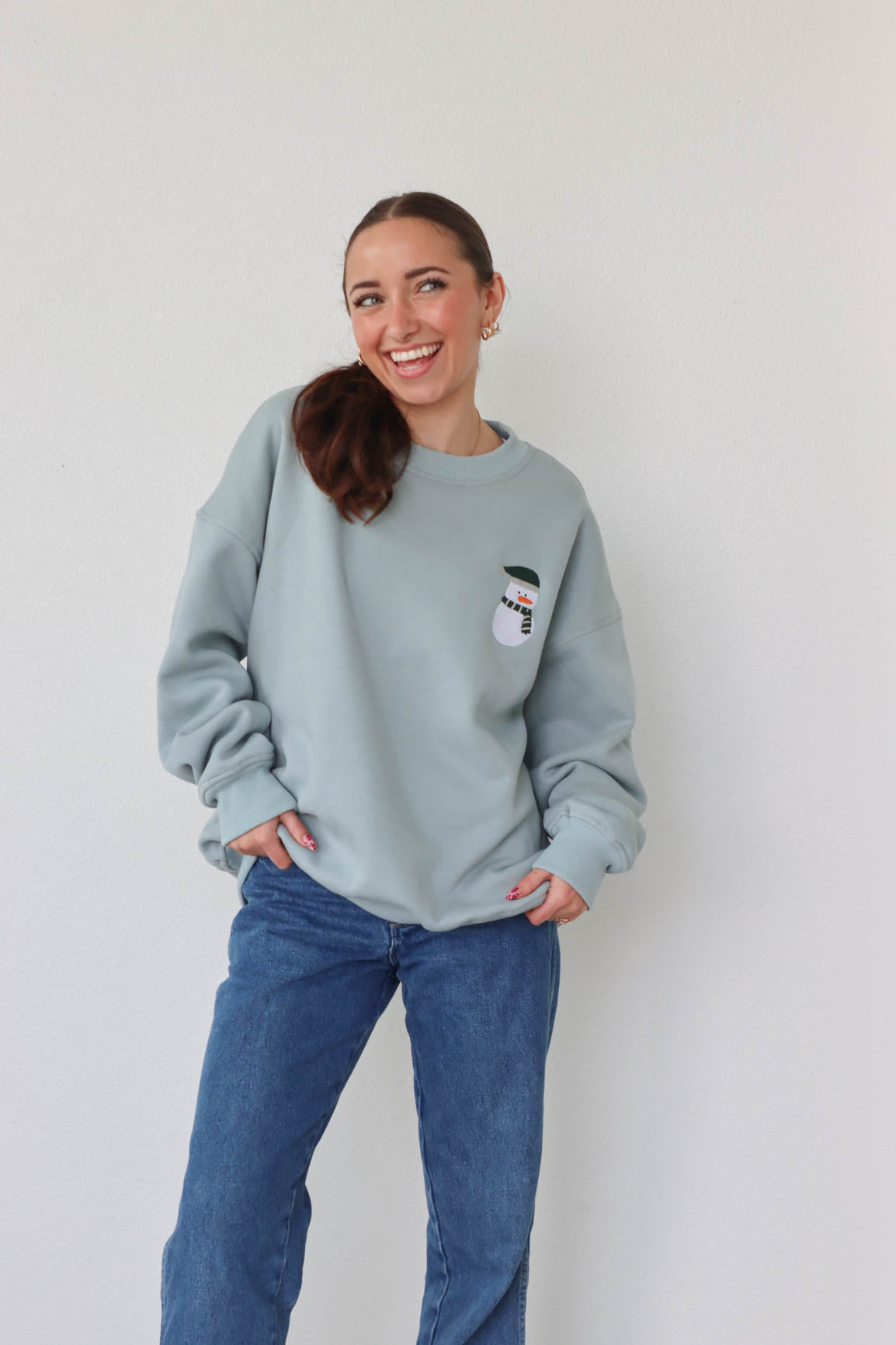 girl wearing light blue snowman crewneck