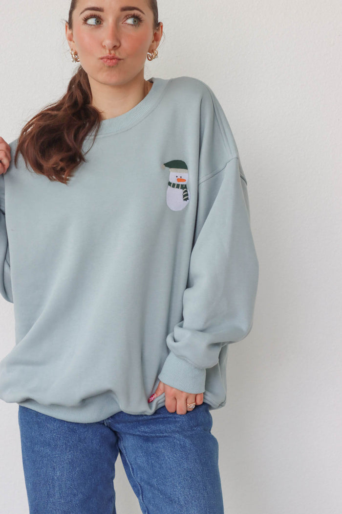 girl wearing light blue snowman crewneck