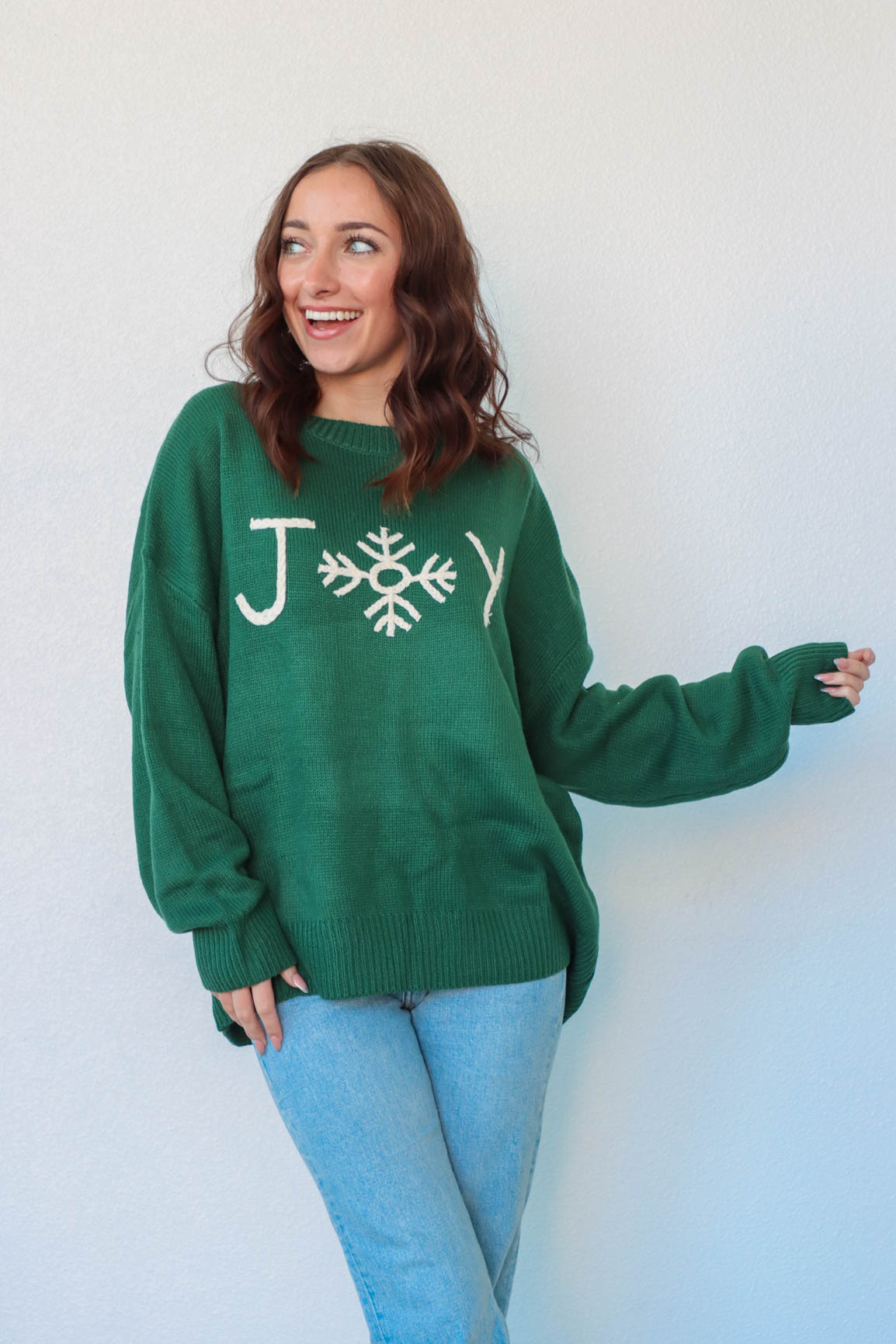 girl wearing green christmas sweater with "joy" graphic