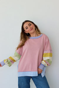 Woman wearing a pink shirt with colorful sleeves against a white background