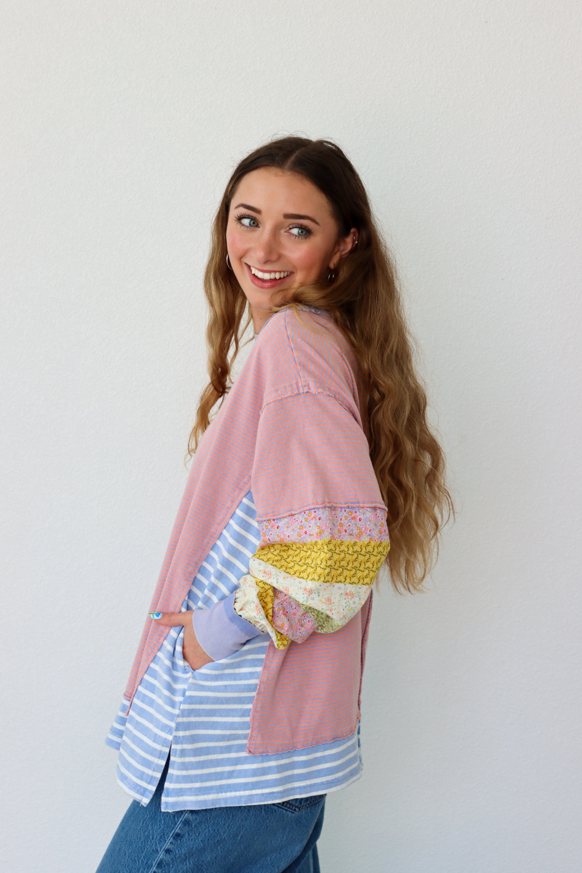 Woman wearing a colorful layered outfit against a white background