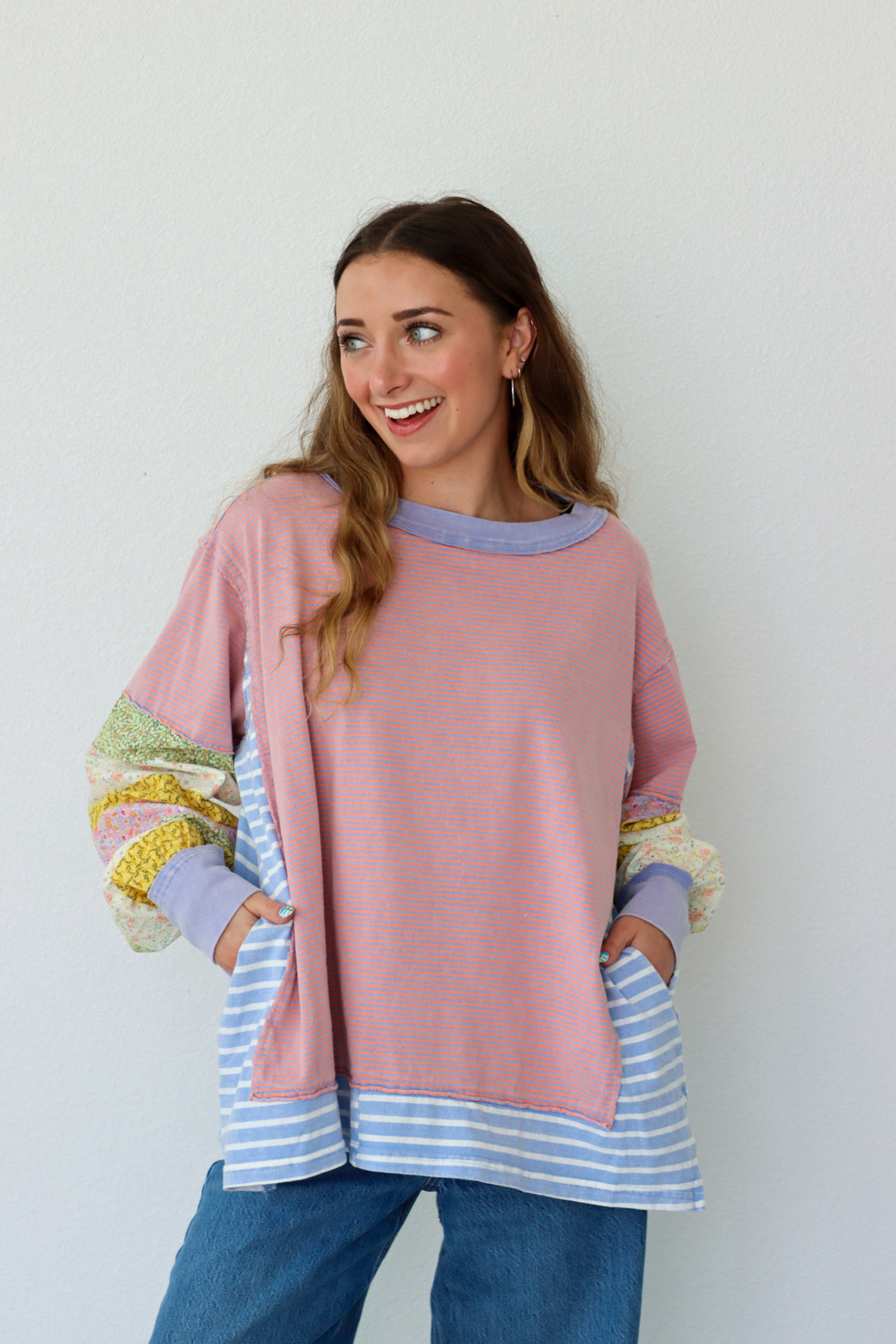 Woman wearing a pink shirt with colorful cuffs and hem against a white background