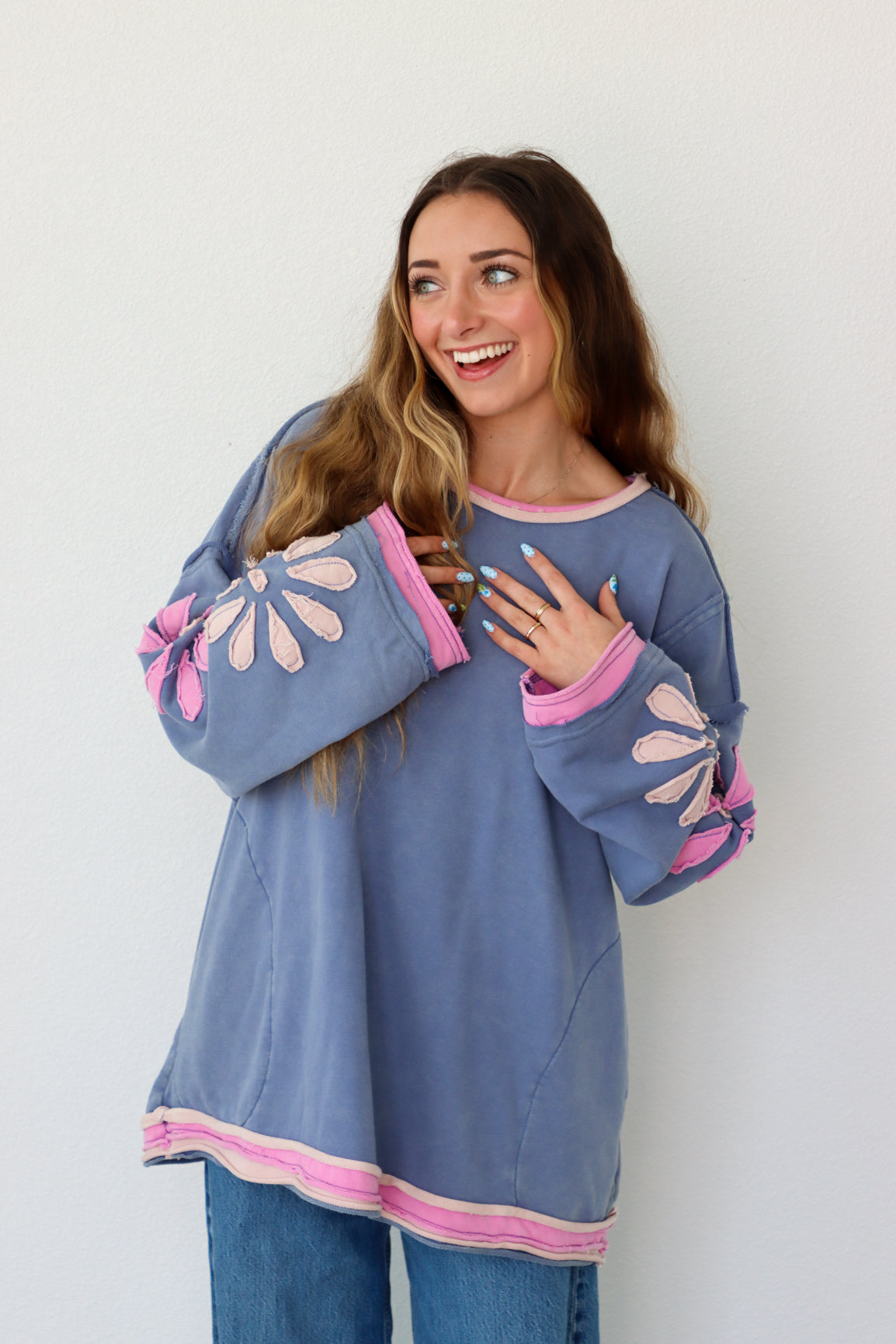 Woman wearing a blue and pink outfit with floral sleeves against a white background