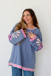 Woman wearing a blue and pink outfit with floral sleeves against a white background