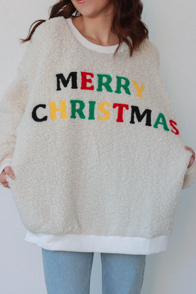 girl wearing cream sherpa crewneck with multicolor "Merry Christmas" patch lettering