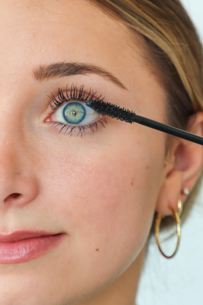 Close-up of a woman applying mascara to her eyelashes.