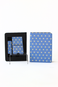 A blue stationery set with a repeating gold star pattern, shown both inside its black presentation box and standing upright on a clear acrylic display stand against a white background.