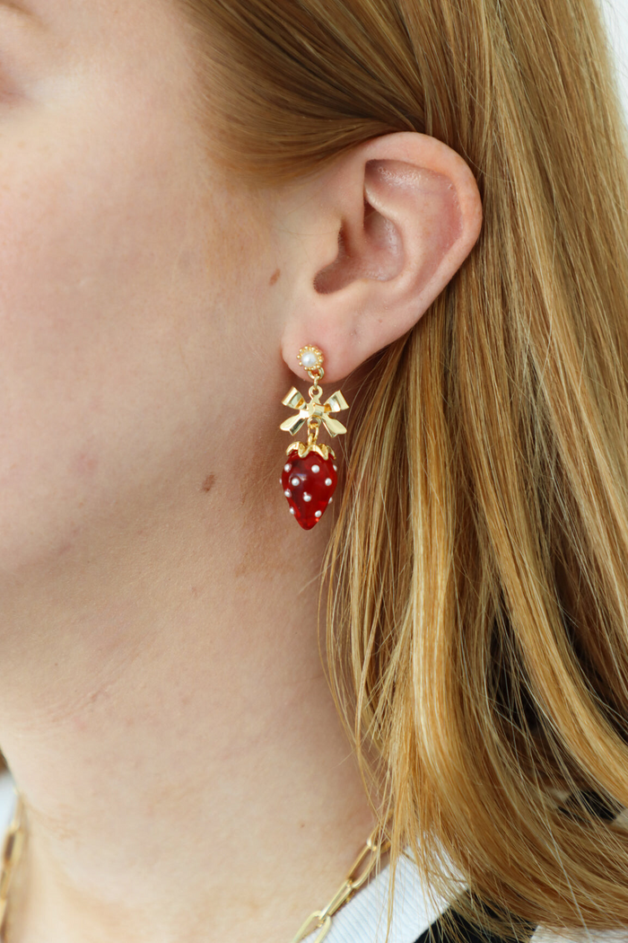 girl wearing gold and red bow and strawberry earrings