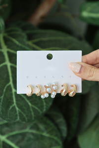 Set of earrings on a display card held against a green leafy background