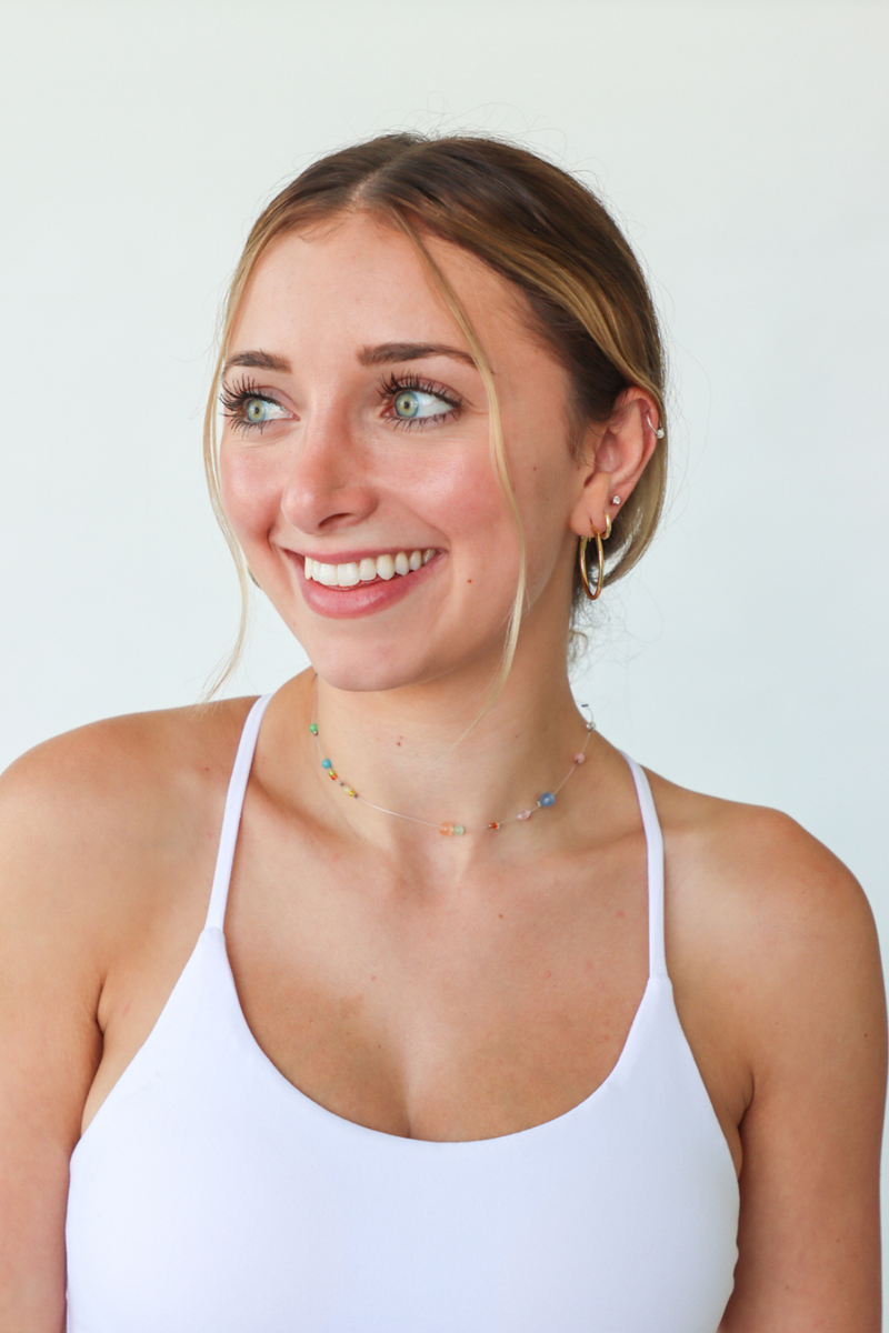 Woman wearing a white tank top against a plain background