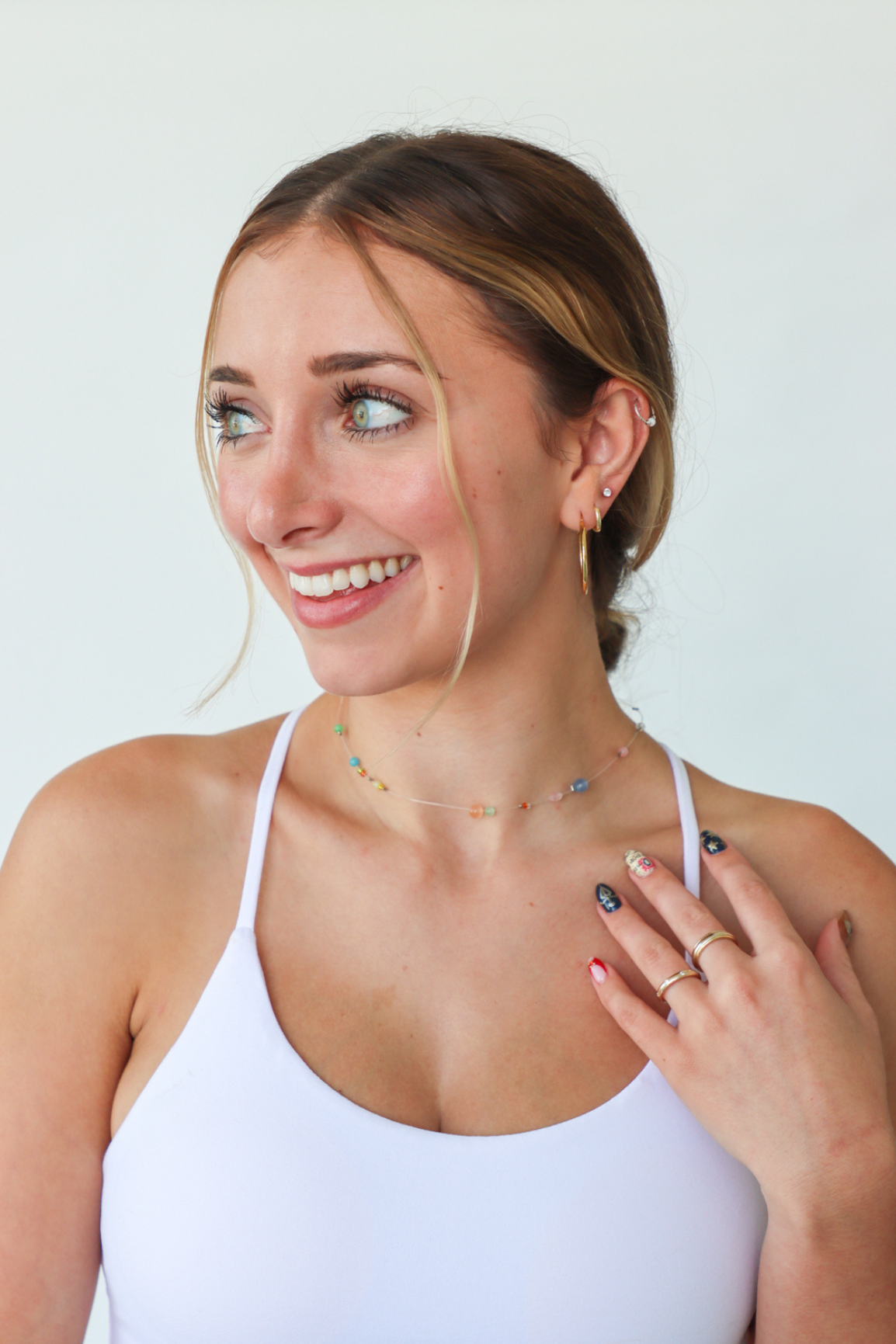 Woman wearing a white tank top with a plain background