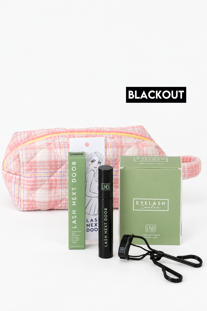 Lash Next Door blackout eyelash extension kit including a pink and white plaid zippered pouch, black applicator tube, green retail box, and black wrist strap, with a BLACKOUT label overlay.