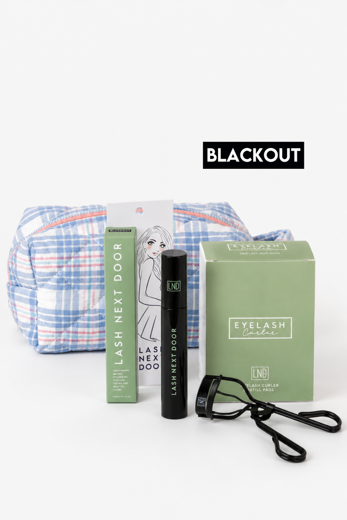 Lash Next Door eyelash extension kit with a plaid carrying pouch, green lash box, black lash wand, and blackey glasses, labeled BLACKOUT on a white background.