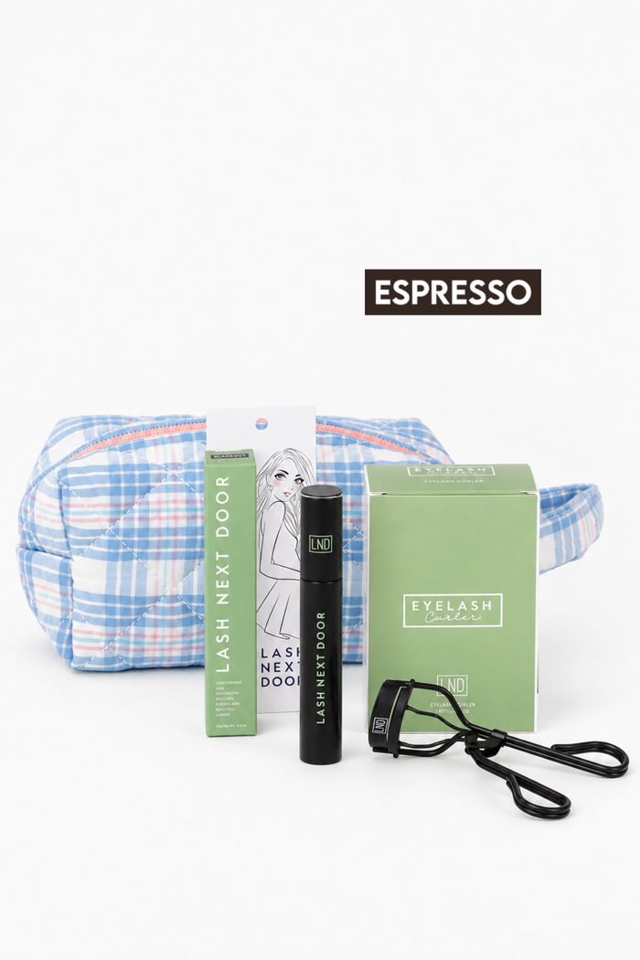 A lash care set on a white background, featuring a blue and white plaid cosmetic pouch, a green tube labeled 'LASH NEXT DOOR', a black mascara tube, a green 'EYELASH' box, and a black eyelash curler. A black label reading 'ESPRESSO' is positioned above the items.