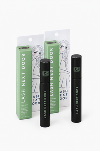 Two black Lash Next Door mascara tubes standing in front of two green and white retail boxes with an illustrated woman on the packaging, photographed on a clean white background.