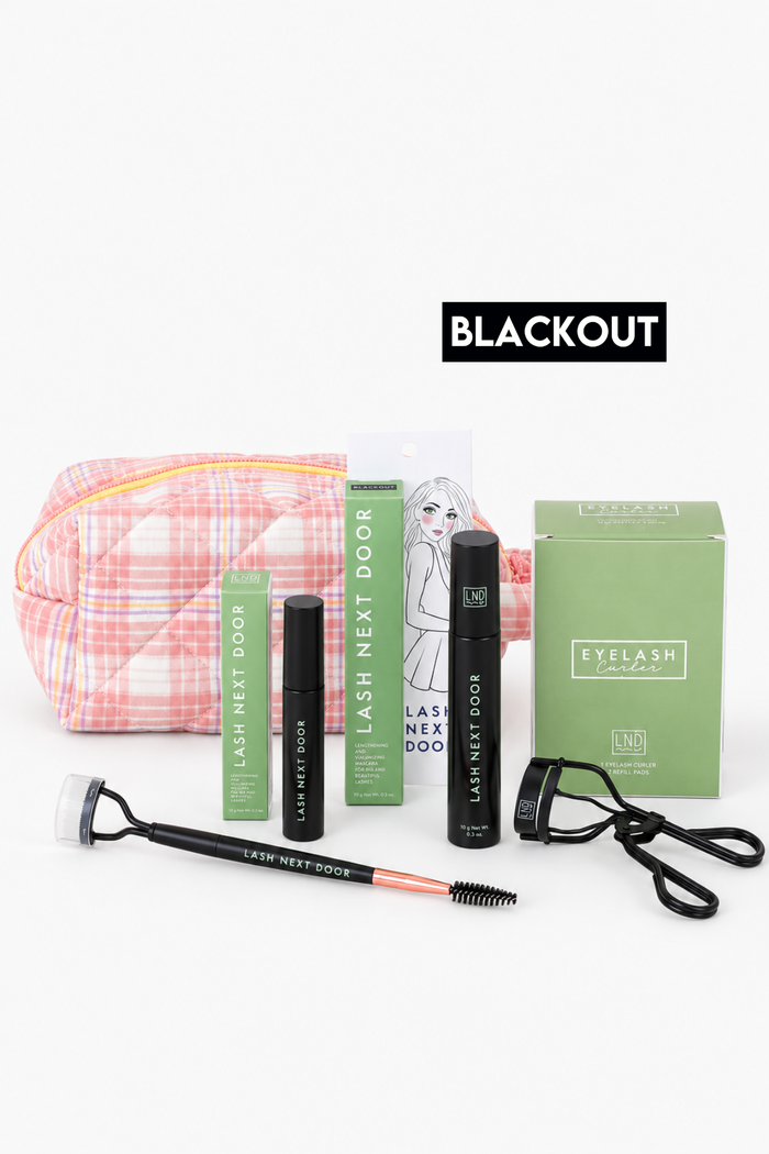 Eyelash extension kit with a pink plaid carrying pouch, black and green tubes, a green box, a spoolie wand, and a black lash comb on a white background with a BLACKOUT text overlay.