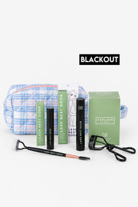 Eyelash extension kit with black lash adhesive, black lash primer, a green lash box, a green instruction booklet, a blue and white plaid makeup bag, a black spoolie, and a black lash comb, arranged on a white background with a black 'BLACKOUT' label above.