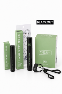 Lash Next Door Eyelash Concealer kit in the shade BLACKOUT, featuring a black tube, green packaging boxes, an eyelash clip, and a black applicator on a white background.