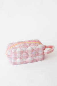 Small pink and white checkered pouch with a yellow zipper on a light gray background