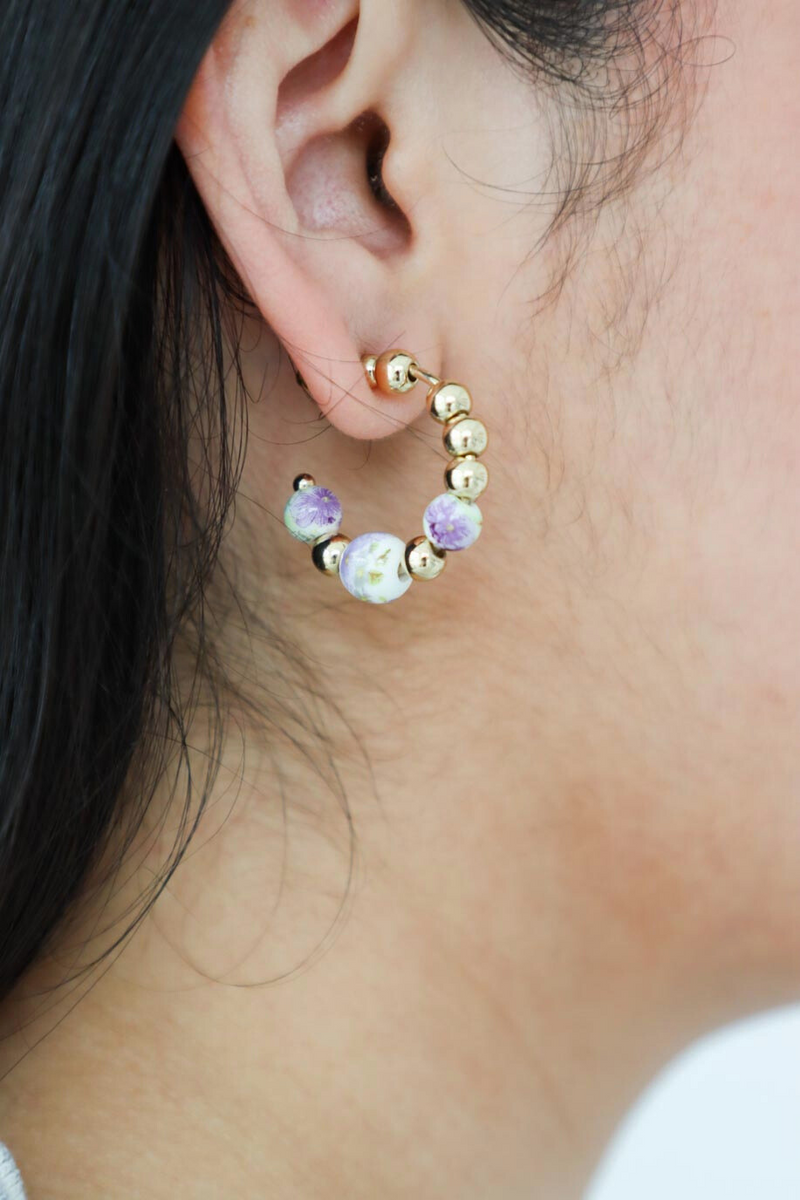 girl wearing gold hoop earrings with floral glass beads