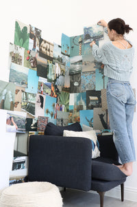 girl hanging up photo on her collage wall that is blue hues of photos