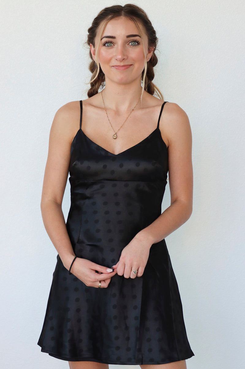 girl wearing black slip dress with polka dot detail