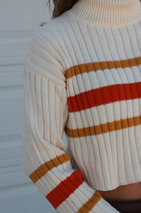 girl wearing cream turtleneck sweater with orange and brown strips