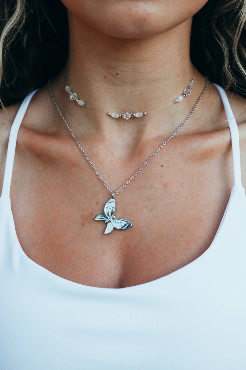 girl wearing large silver butterfly necklace