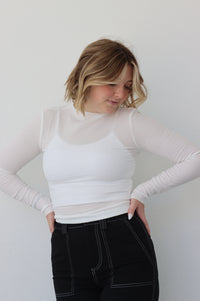 girl poses in a sheer white long sleeve top