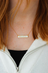 girl wearing white and gold "mama" necklace