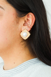 girl wearing gold and pearl stud earrings