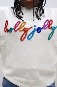 close up of "holly jolly" text on sweater in multicolor shimmery tinsel