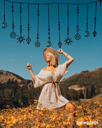 girl posing in field of flowers with black hanging jewel doodles above her