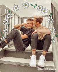 two boys sitting on stairs with an arch of flowers around them