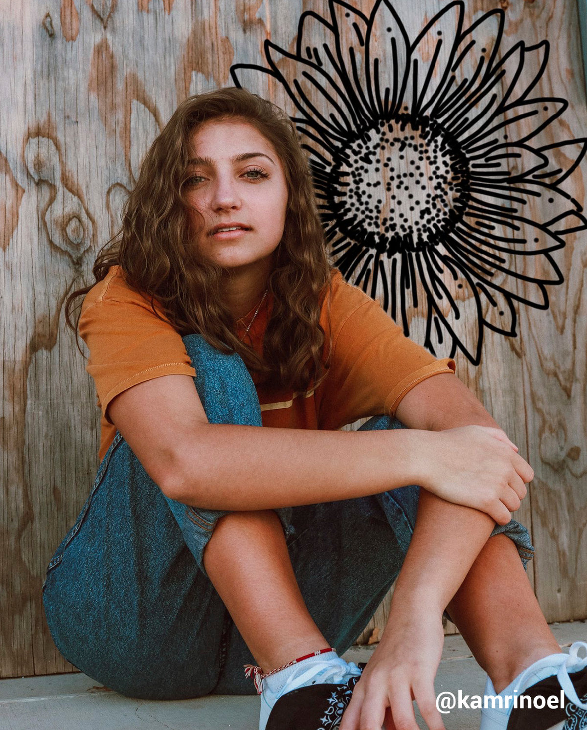 girl sitting on the ground with a black drawn sunflower behind her