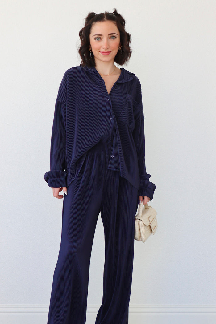 girl wearing navy blue outfit set with long sleeve button down blouse and elastic waist palazzo pants. Both in a pleated crinkle fabric