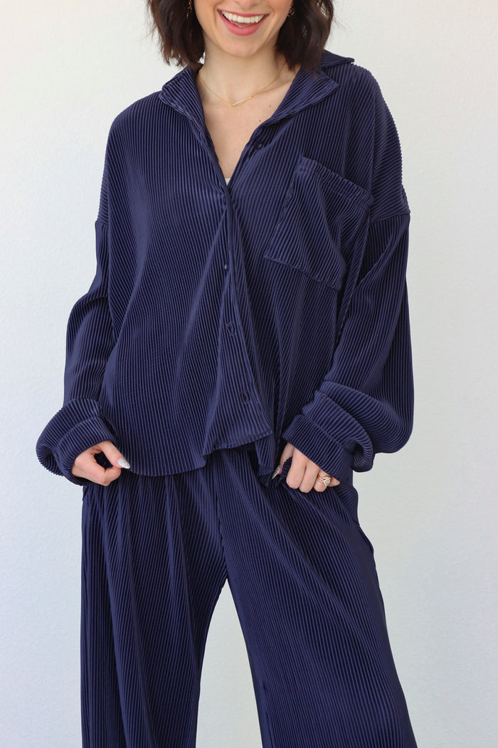 girl wearing navy blue outfit set with long sleeve button down blouse and elastic waist palazzo pants. Both in a pleated crinkle fabric