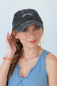 girl wearing baseball cap in charcoal with the word "feelings" stitched on to it