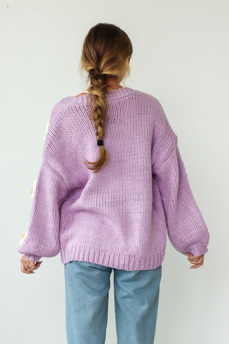 girl wearing a purple knit cardigan with daisies